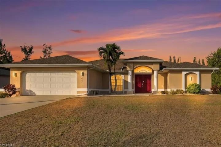 View of front of house featuring stucco siding, driveway, a lawn, and a garage