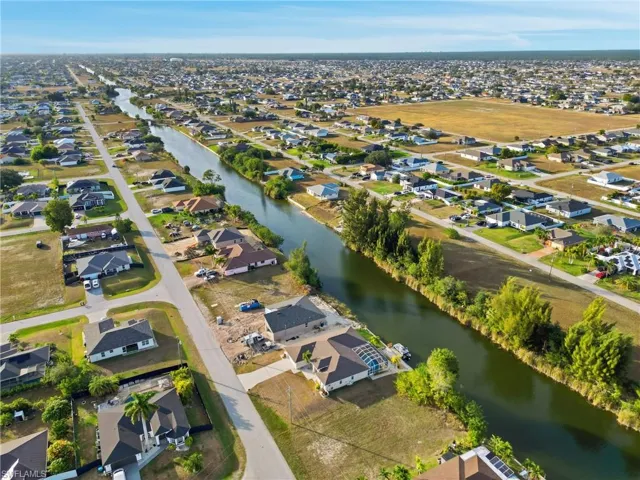Aerial view of property and surrounding area featuring nearby suburban area and a large body of water