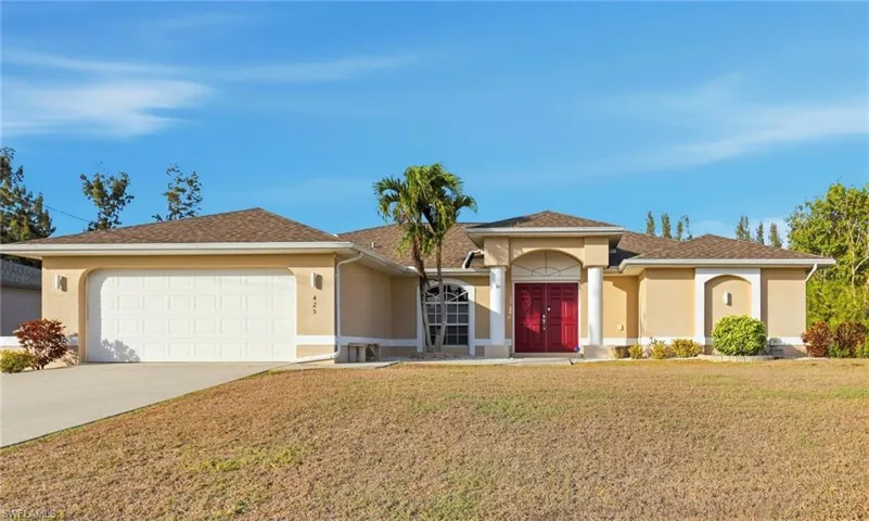 View of front facade with stucco siding, concrete driveway, a front lawn, and a garage