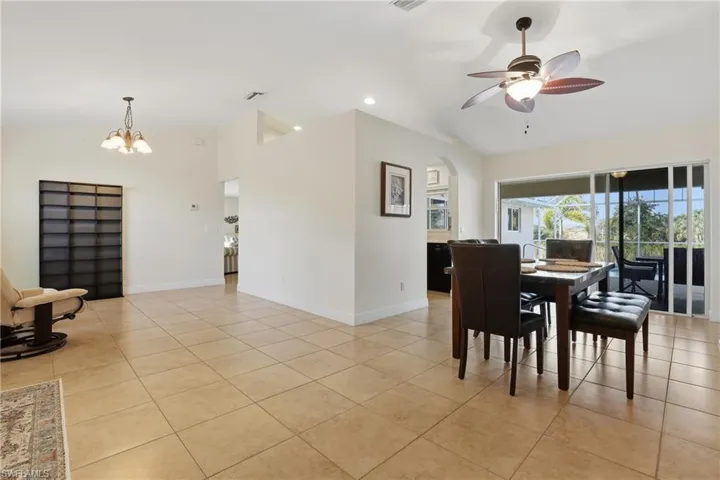 Dining space with ceiling fan, light tile patterned floors, a chandelier, recessed lighting, and high vaulted ceiling