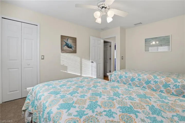 Carpeted bedroom featuring ceiling fan and a closet
