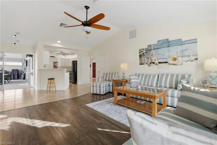 Living area with light wood-type flooring, ceiling fan, and high vaulted ceiling