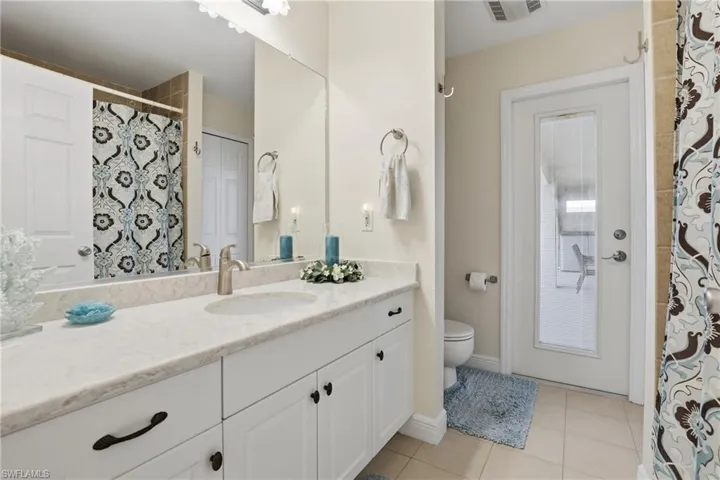 Bathroom with curtained shower, vanity, and light tile patterned floors