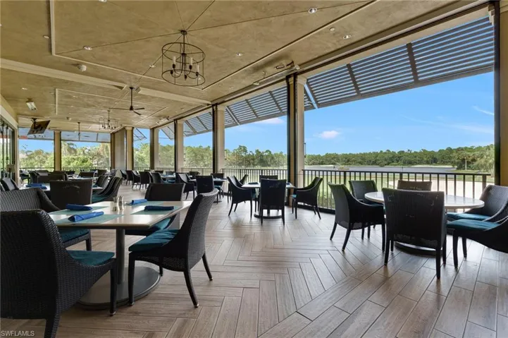 Covered outdoor dining terrace featuring herringbone wood-finish flooring, metal railing, retractable sun shades, and recessed lighting