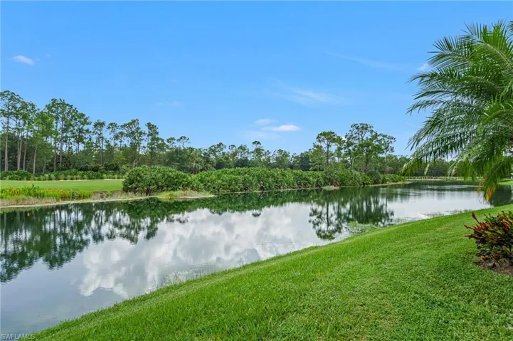Waterfront lot featuring a manicured lawn, native landscaping, and mature trees
