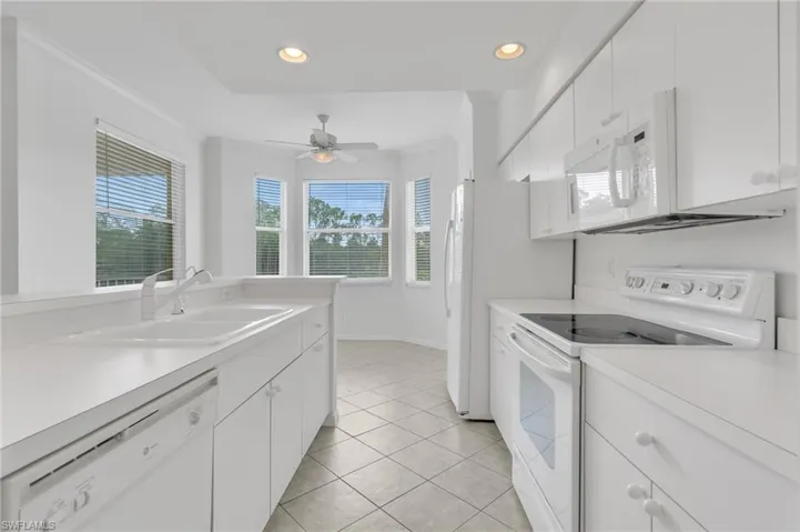 Kitchen featuring white cabinetry, solid-surface countertops, tile flooring, recessed lighting, and a bay window