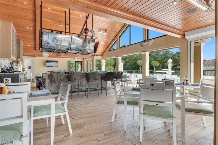 Open-air pavilion featuring a vaulted wood-plank ceiling, large fixed-glass clerestory windows, and wood-finish tile flooring