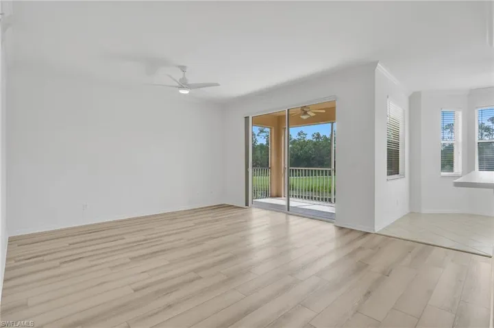 Neutral-toned vinyl flooring, ceiling fan with integrated lighting, sliding glass door, covered lanai, and bay window area