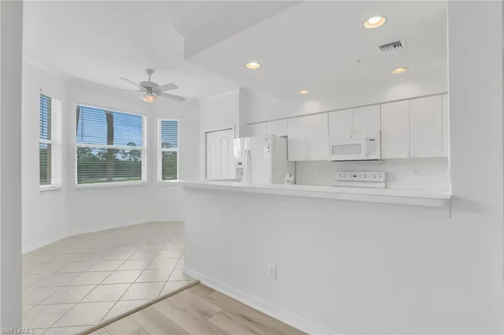 Kitchen featuring white cabinetry, a breakfast bar, recessed lighting, tile flooring, and wood-finish flooring