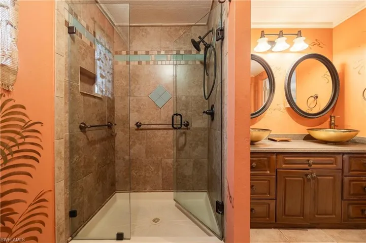 Bathroom with tile patterned flooring, an enclosed shower, ornamental molding, and vanity