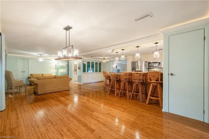 Dining room featuring ornamental molding, ceiling fan with notable chandelier, and light wood-type flooring