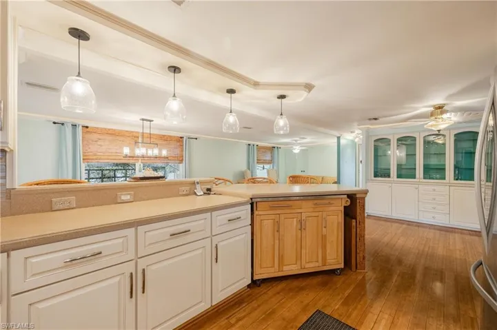 Kitchen with ornamental molding, light hardwood / wood-style flooring, decorative light fixtures, and ceiling fan