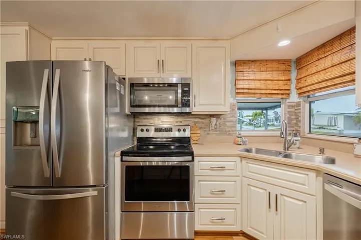 Kitchen with sink, appliances with stainless steel finishes, white cabinets, and decorative backsplash