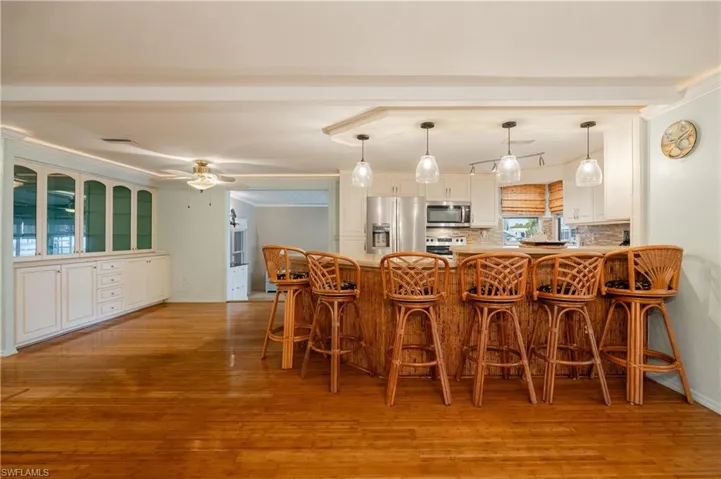 Kitchen with a kitchen breakfast bar, wood-type flooring, appliances with stainless steel finishes, kitchen peninsula, and ceiling fan