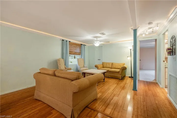Living room with crown molding, ceiling fan, and light wood-type flooring