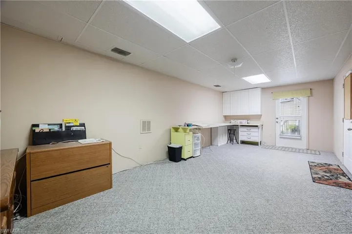 Home office with light colored carpet and a drop ceiling