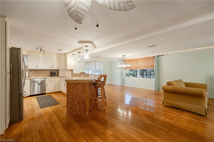 Kitchen featuring pendant lighting, light hardwood / wood-style flooring, a kitchen bar, backsplash, and appliances with stainless steel finishes
