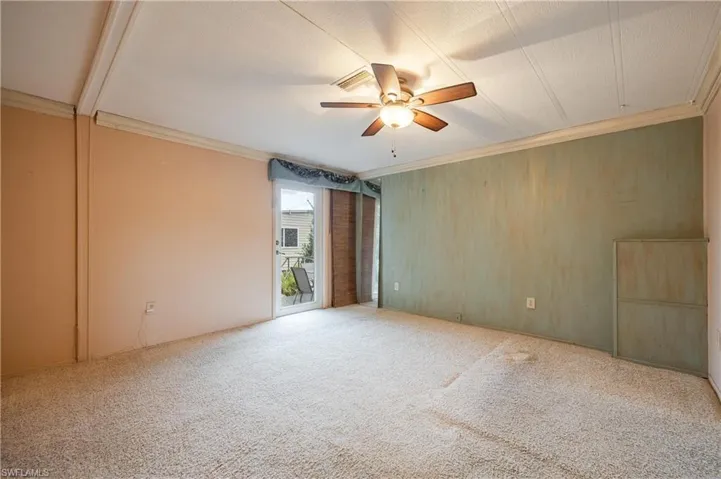 Empty room featuring ceiling fan, carpet floors, and wooden walls