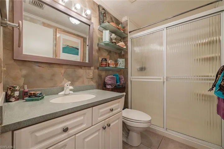 Bathroom with tile patterned floors, toilet, a shower with door, and vanity