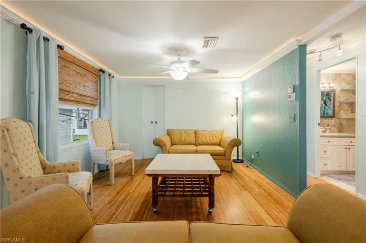 Living room featuring ceiling fan, hardwood / wood-style flooring, and ornamental molding