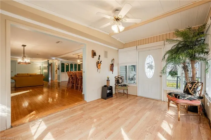 Entryway with ceiling fan with notable chandelier and light wood-type flooring