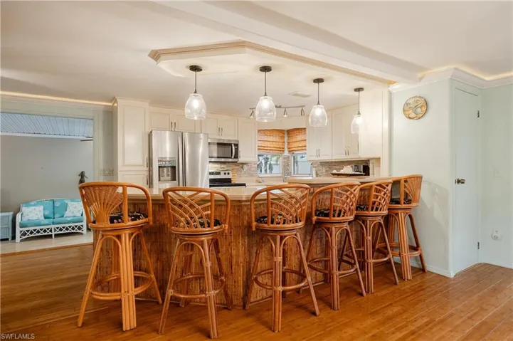 Kitchen with a kitchen bar, pendant lighting, hardwood / wood-style floors, and appliances with stainless steel finishes