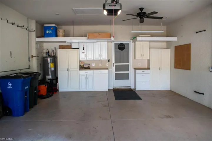 Garage featuring electric water heater, ceiling fan, and a garage door opener