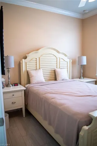 Bedroom with dark hardwood / wood-style flooring, ceiling fan, and ornamental molding