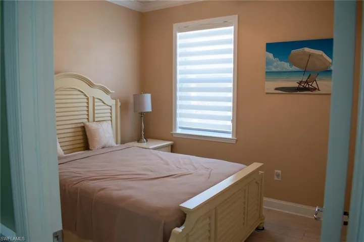 Bedroom with light hardwood / wood-style floors, ornamental molding, and multiple windows