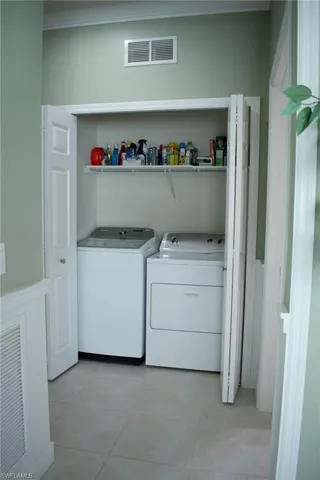 Laundry room featuring crown molding, light tile patterned flooring, and washer and dryer