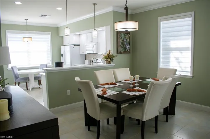Tiled dining space with plenty of natural light and ornamental molding