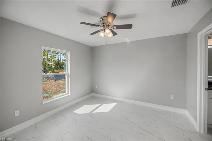 Empty room with light marble finish floors and a ceiling fan