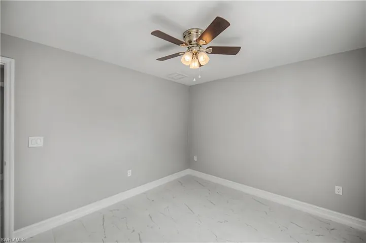 Unfurnished room with light marble finish floors and ceiling fan