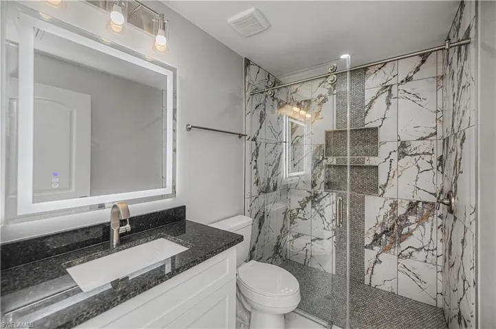 Full bathroom featuring vanity and a marble finish shower