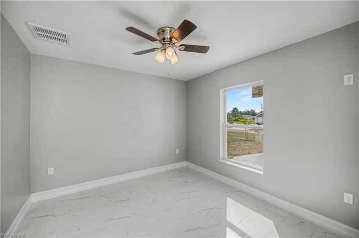 Spare room featuring light marble finish floors and a ceiling fan