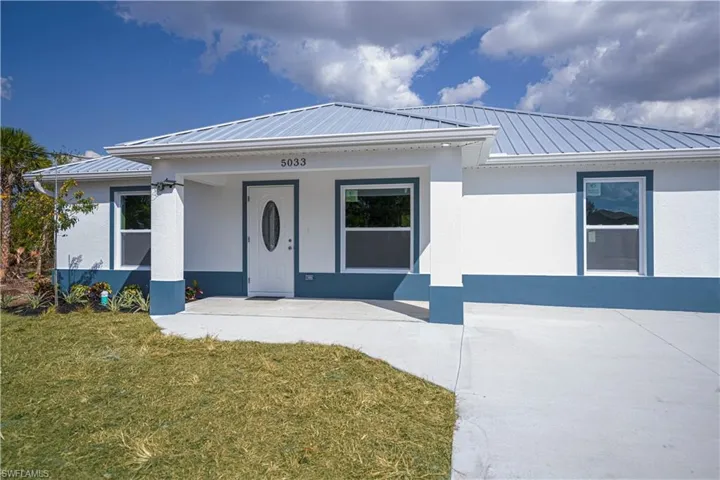 View of front of house with a front lawn, a metal roof, stucco siding, and covered porch