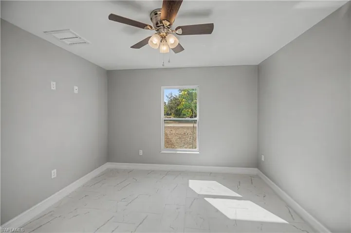 Unfurnished room with light marble finish floors and a ceiling fan