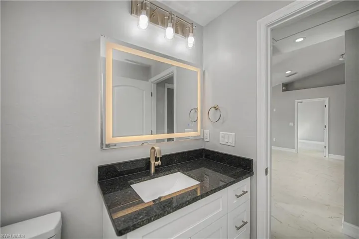Half bathroom with vanity, vaulted ceiling, and recessed lighting