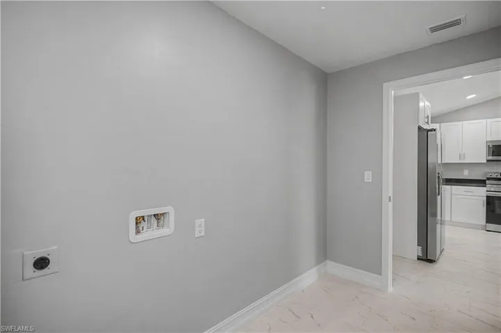 Laundry room with lofted ceiling, light marble finish floors, hookup for an electric dryer, and washer hookup