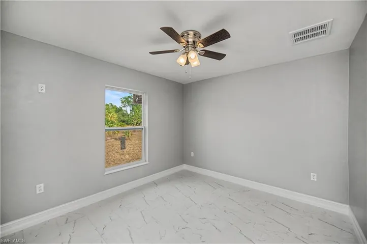 Unfurnished room with light marble finish flooring and ceiling fan