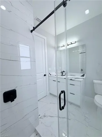 Bathroom featuring vanity, toilet, and a shower with door