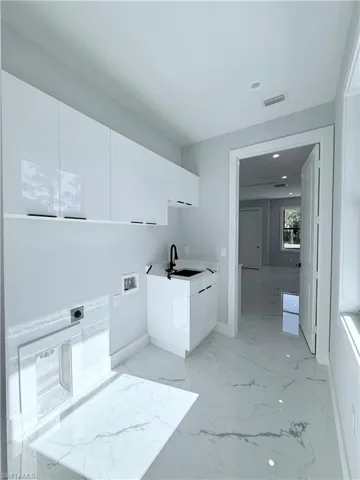Laundry room with electric dryer hookup, cabinets, sink, and washer hookup