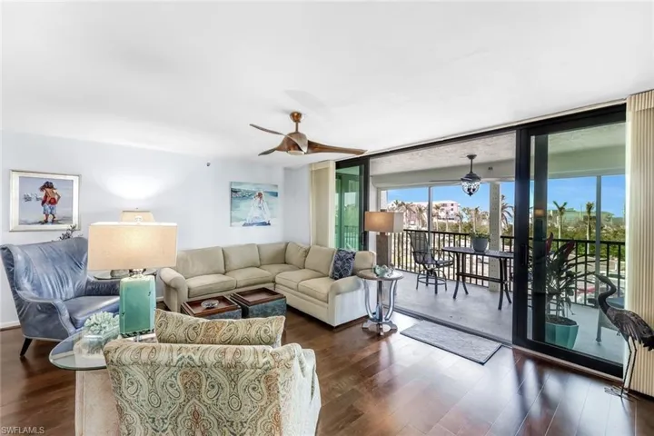 Living area with a wall of windows, a ceiling fan, and wood finished floors