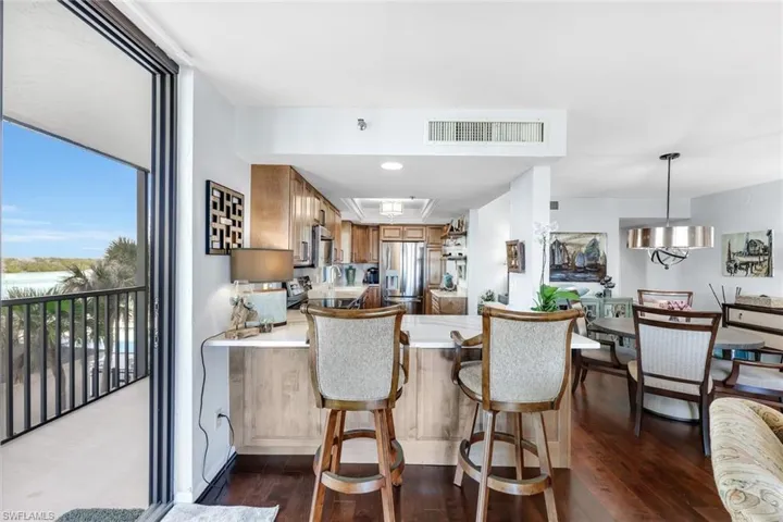 Kitchen with brown cabinets, light countertops, a peninsula, stainless steel fridge, and dark wood-style floors