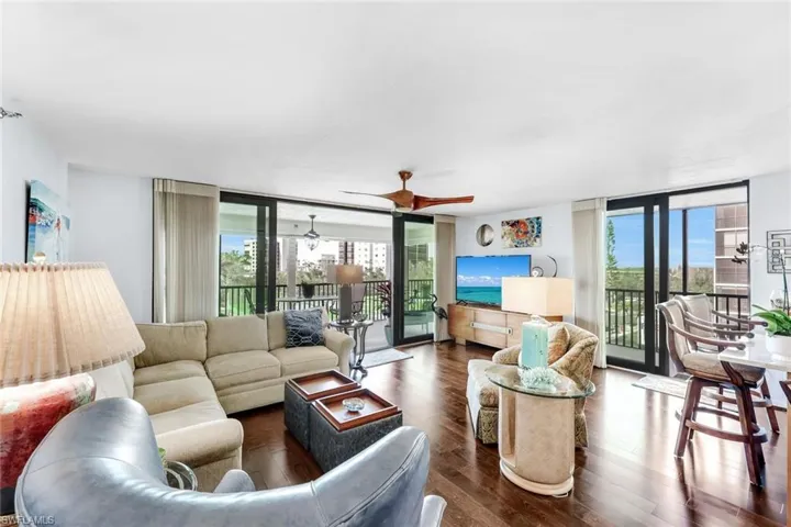 Living room featuring floor to ceiling windows, wood finished floors, plenty of natural light, and a ceiling fan