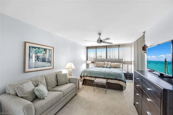 Bedroom with light colored carpet and a ceiling fan