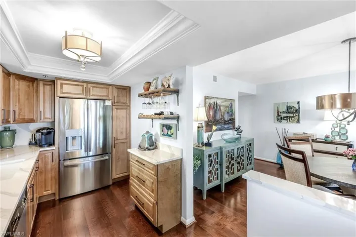 Kitchen featuring stainless steel appliances, open shelves, light stone countertops, dark wood-type flooring, and ornamental molding