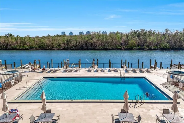 Community pool featuring a patio area, a water view, and view of wooded area