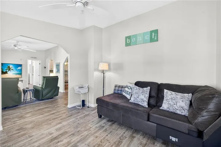 Living area featuring ceiling fan, wood finished floors, and arched walkways