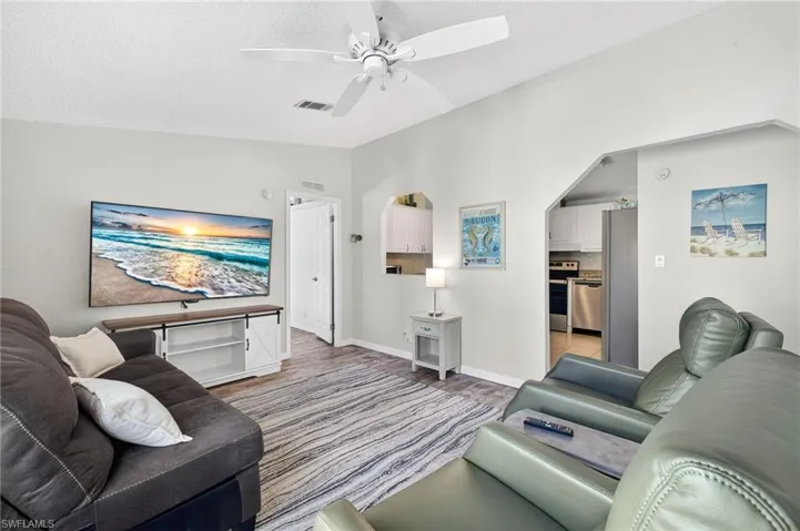 Living room featuring lofted ceiling, ceiling fan, and light wood-style flooring